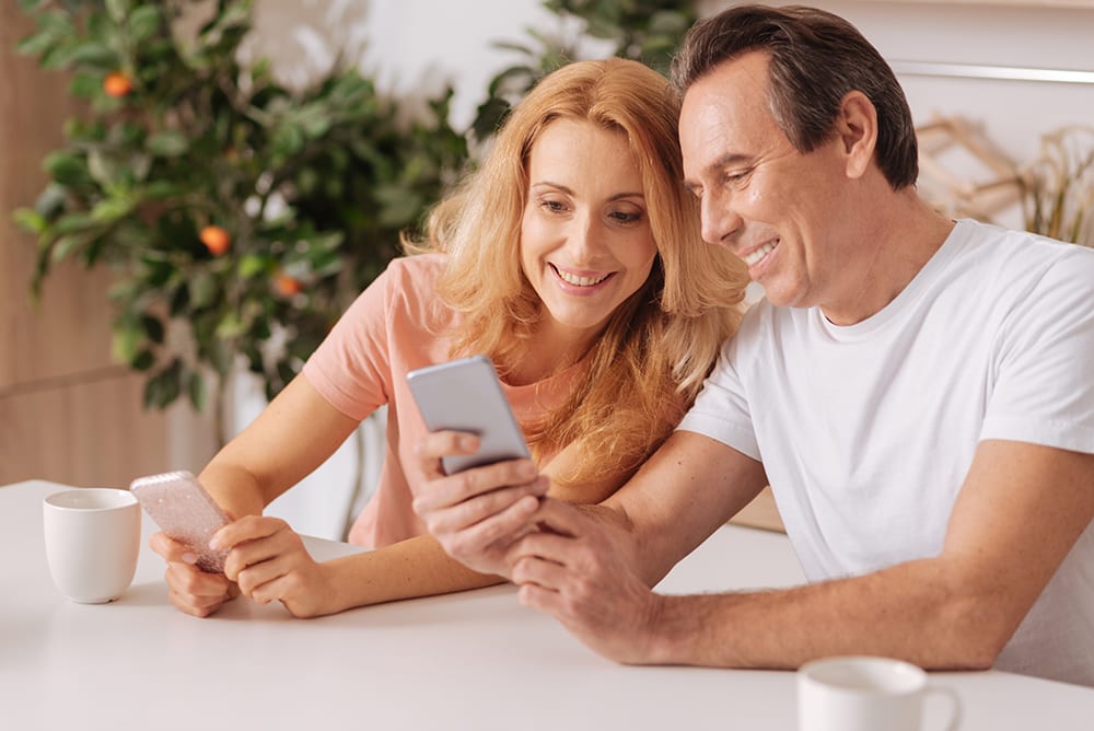 two people looking at a smartphone and smiling